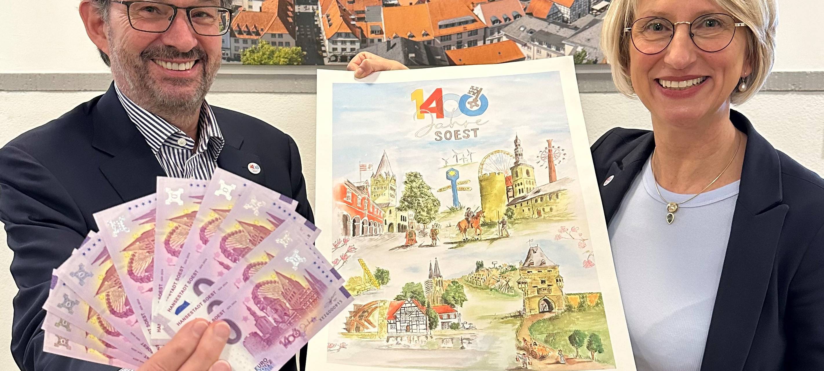 Soests Bürgermeister Dr. Eckhard Ruthemeyer und Carolin Brautlecht, Geschäftsführerin der Wirtschaft und Marketing Soest GmbH, präsentieren die Souvenirs zum Stadtjubiläum.
